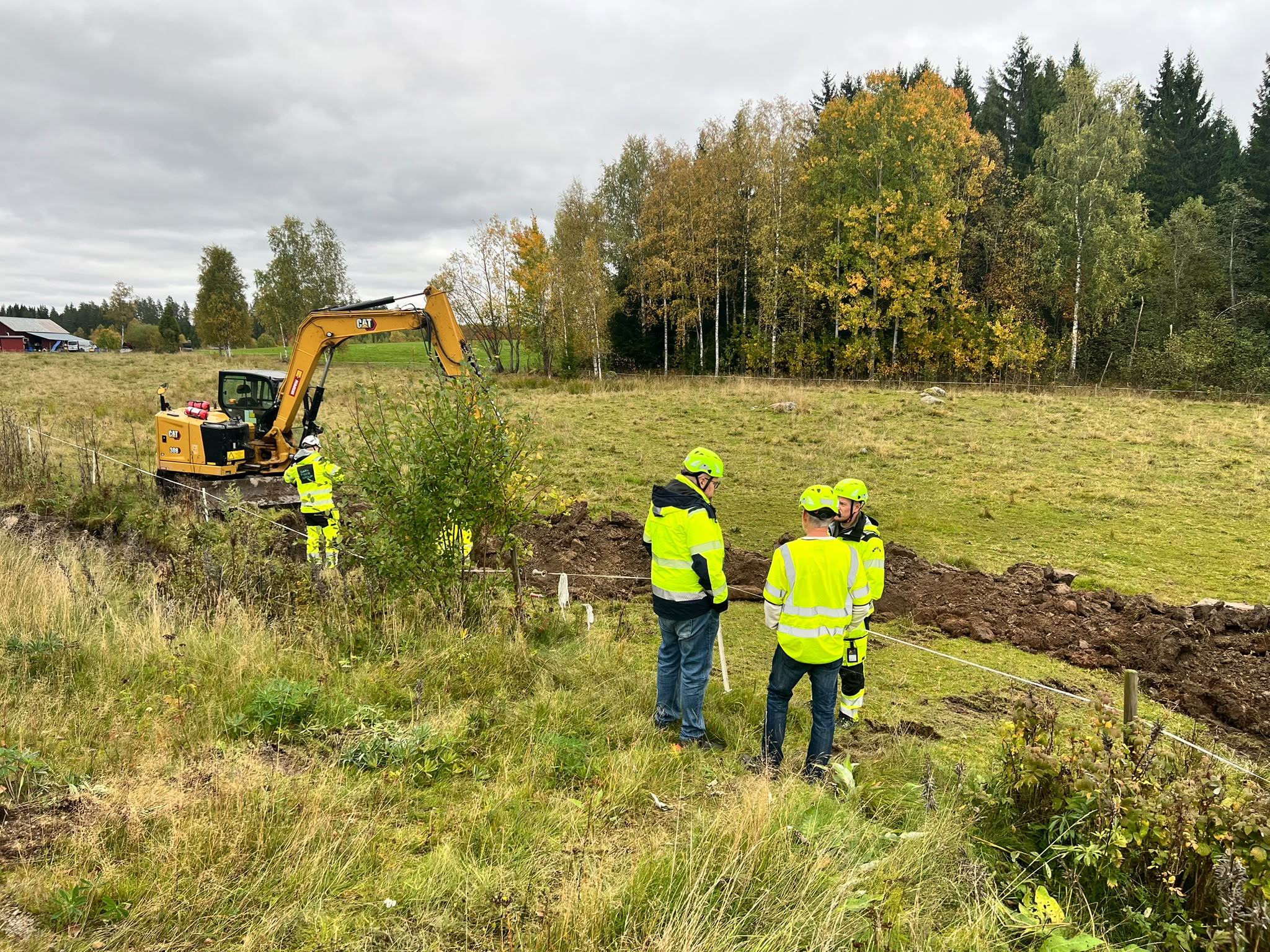 Site team reviewing the trench route beside an excavator